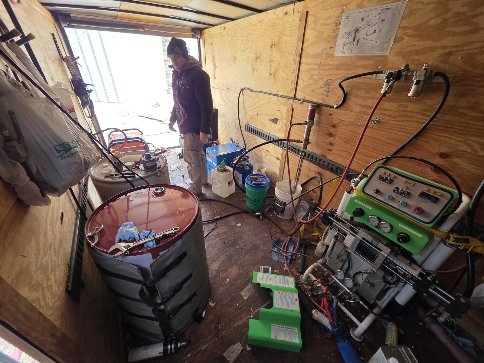 Compressor, hoses, and safety gear staged and ready inside our spray foam trailer.